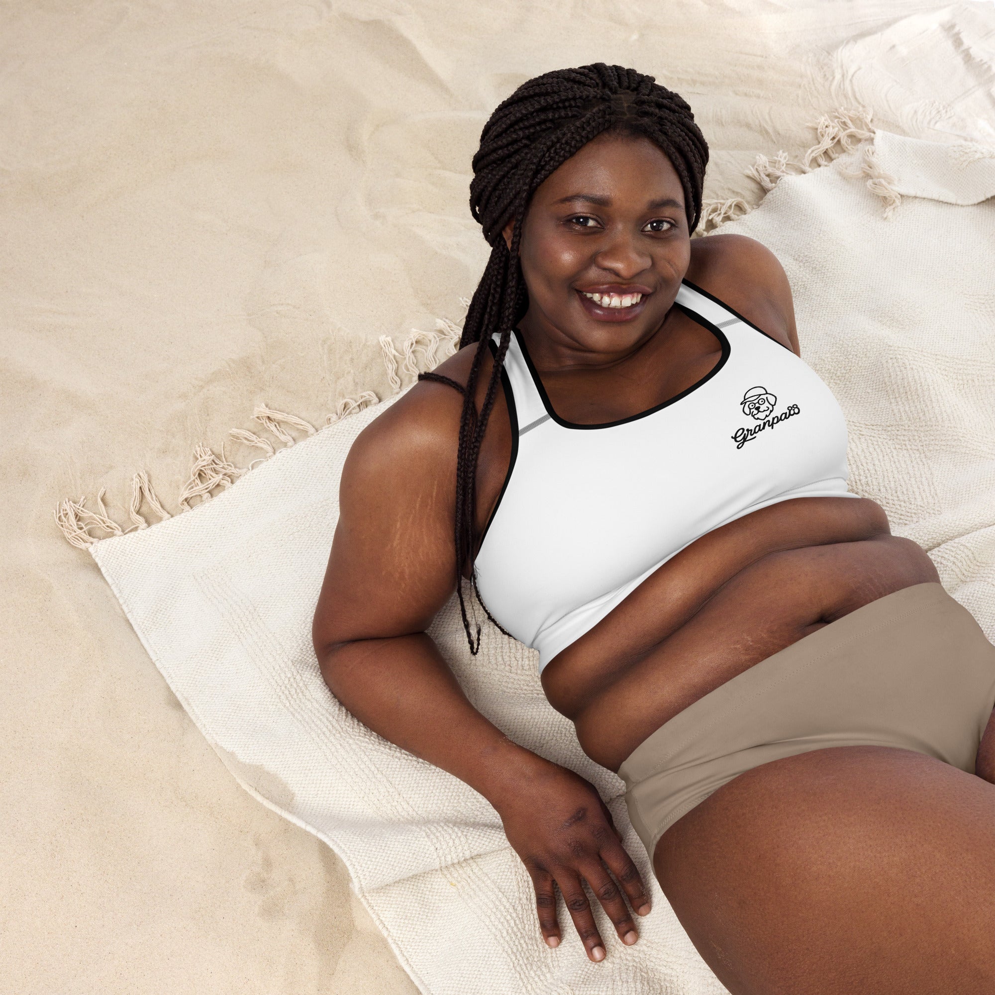 Woman wearing a white tank top and beige shorts on a beige blanket