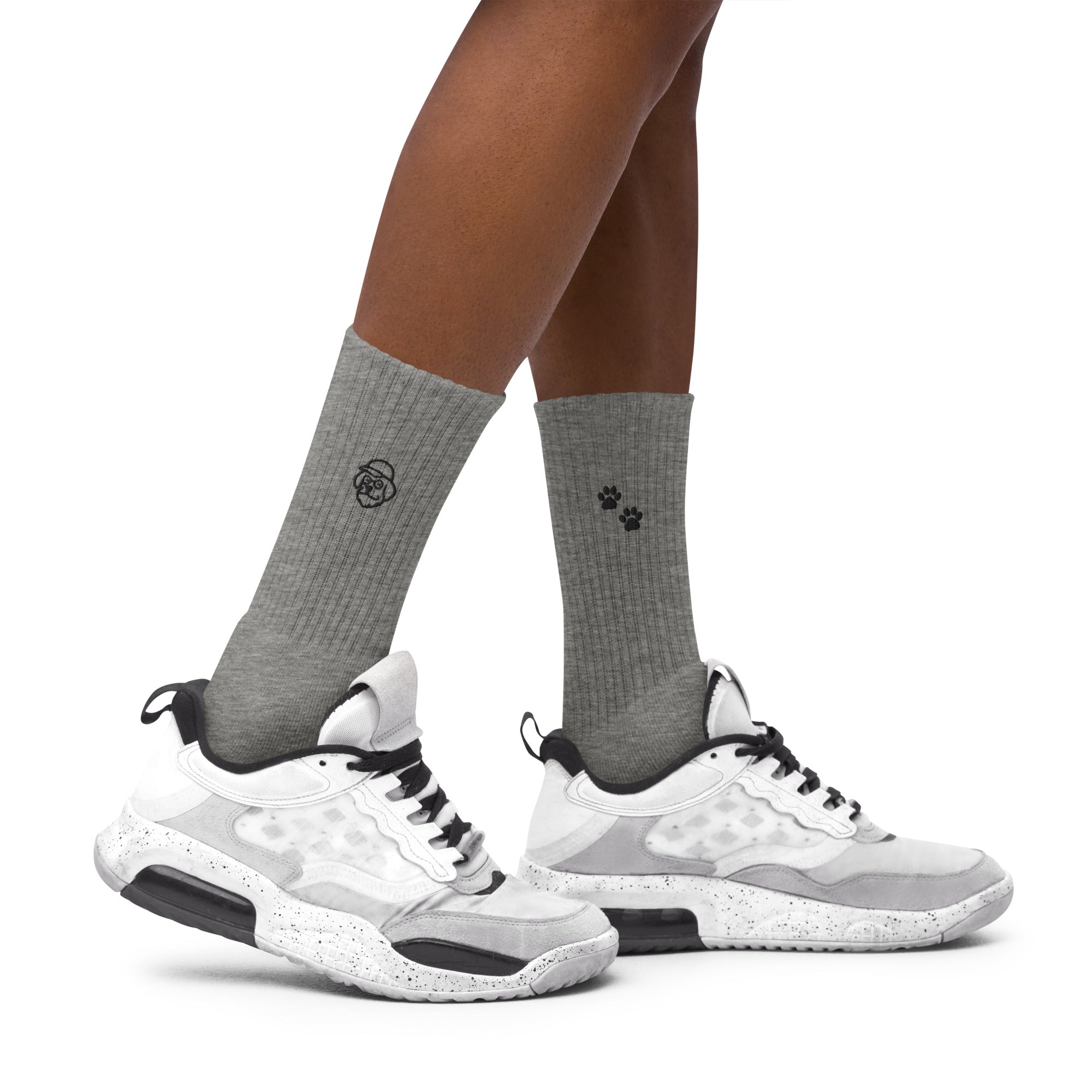 Gray socks with black paw print design worn with white athletic shoes on a white background