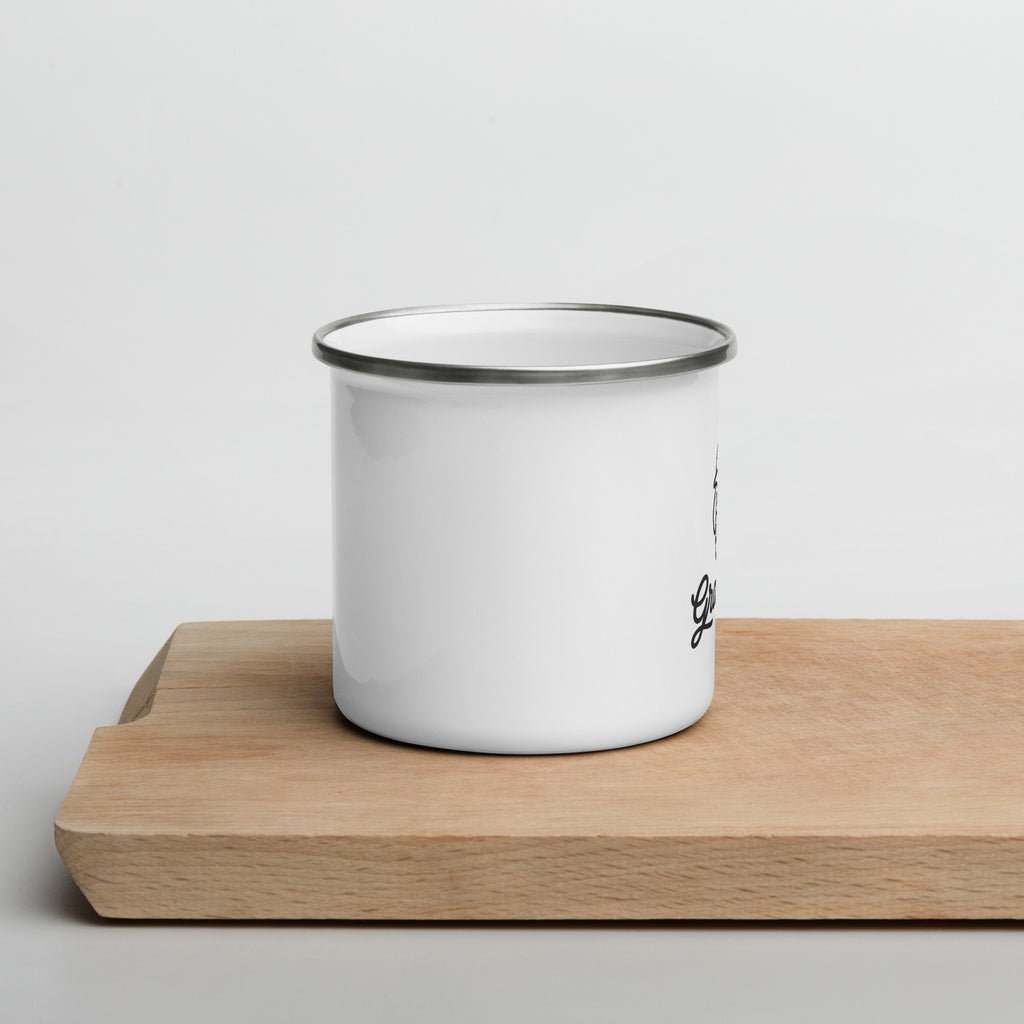 White enamel mug with black rim on a wooden surface against a light gray background