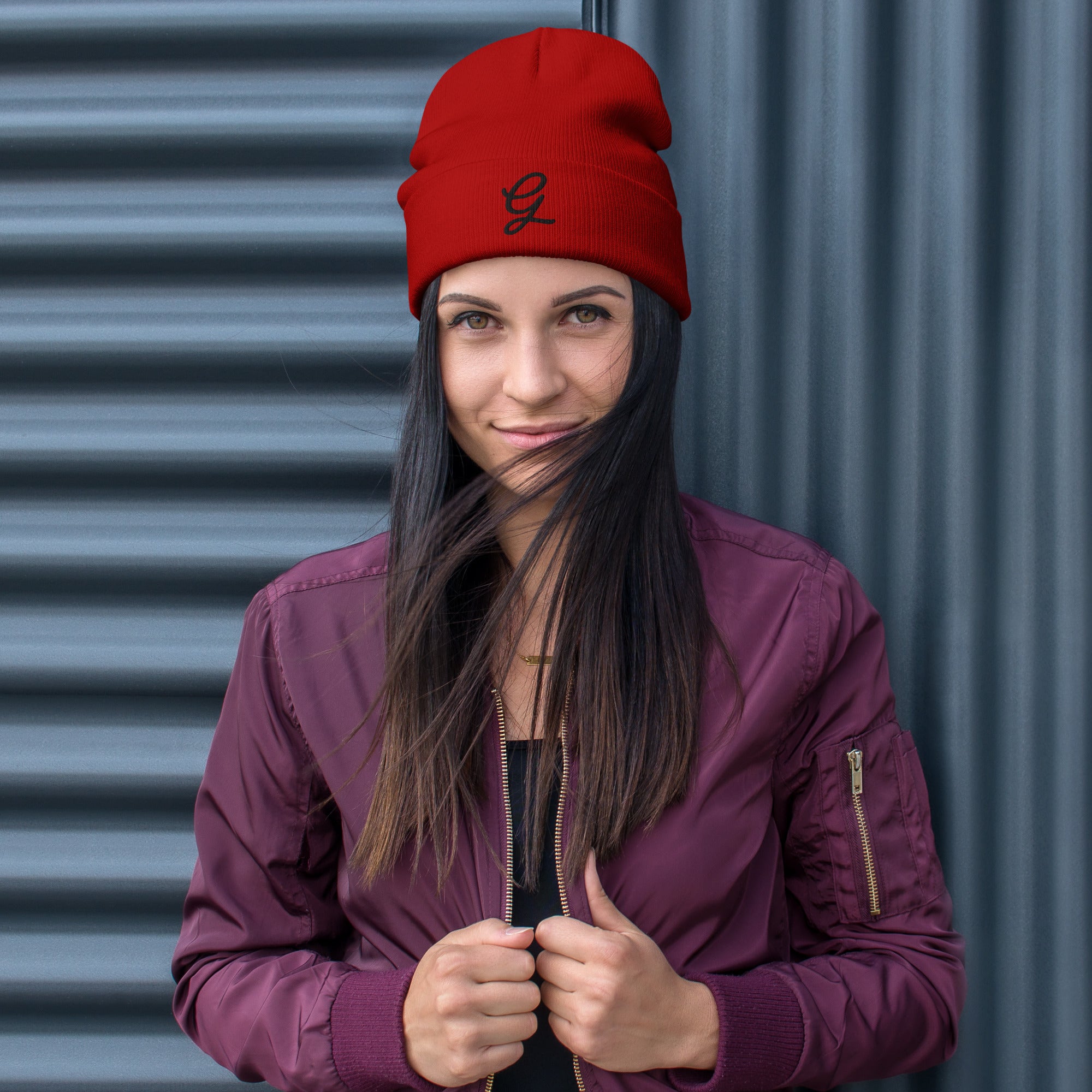 Woman wearing a red beanie and purple jacket against a metallic background