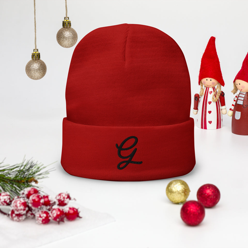 Red beanie with a black letter 'G' on a white background with Christmas decorations.