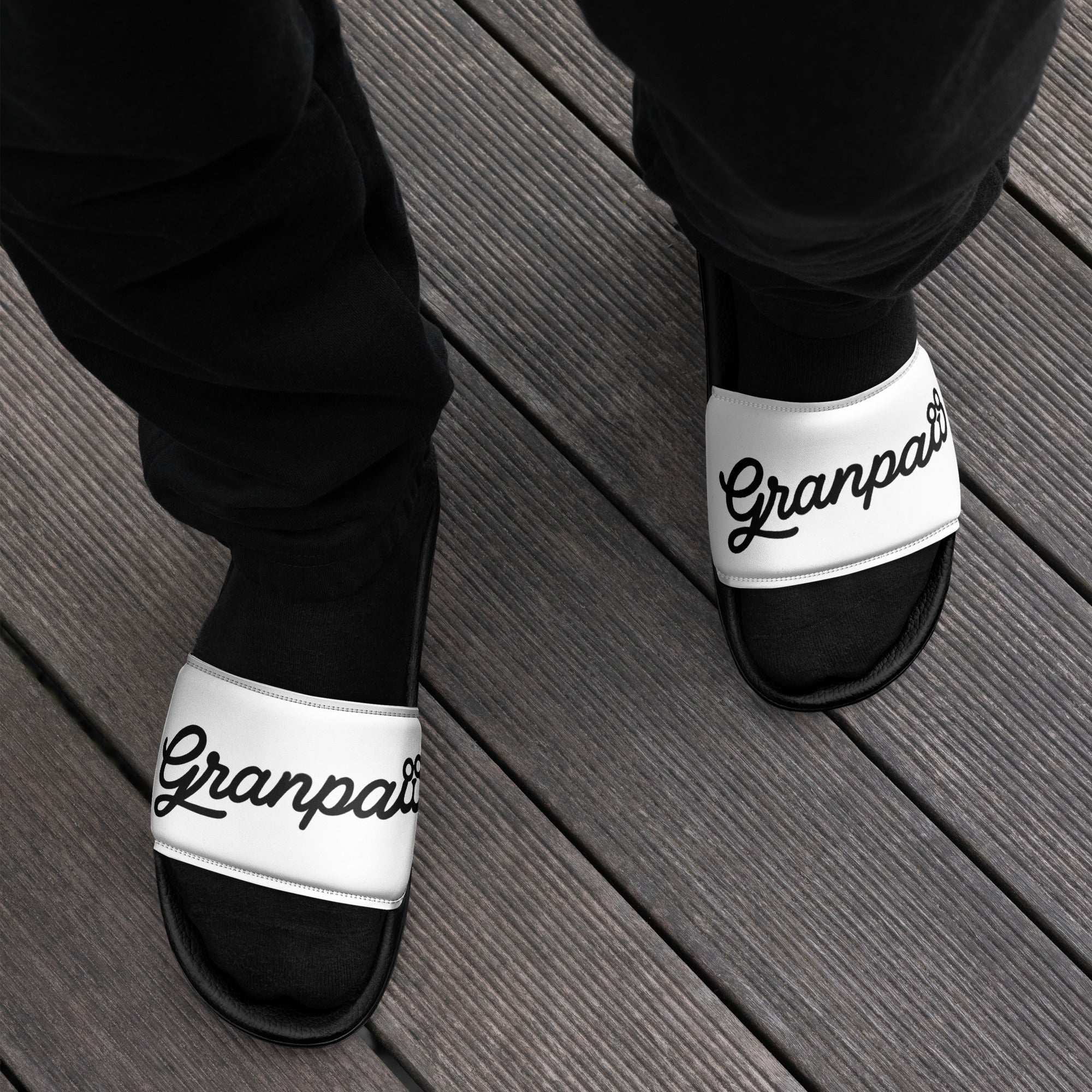 Black and white sandals with 'Granpa' text on a wooden floor