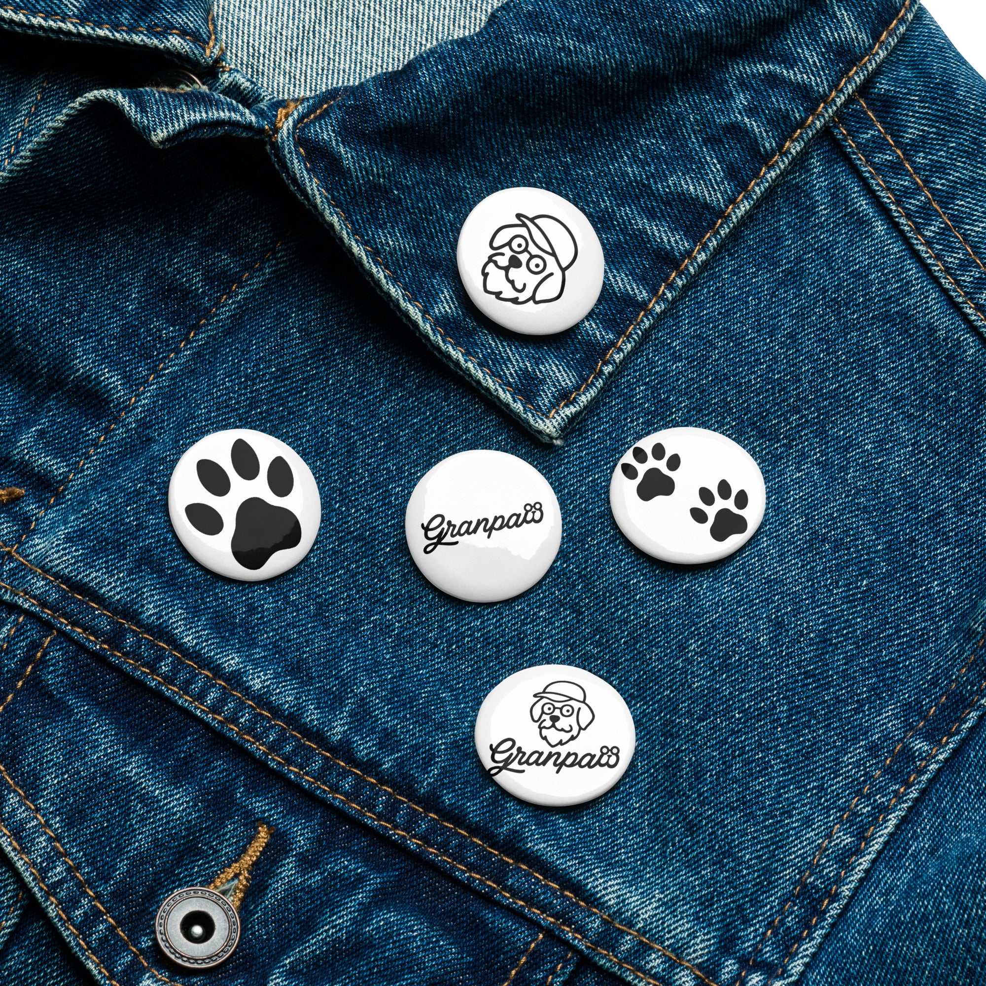 Set of pins with paw prints and 'Granpa' text on a denim jacket.