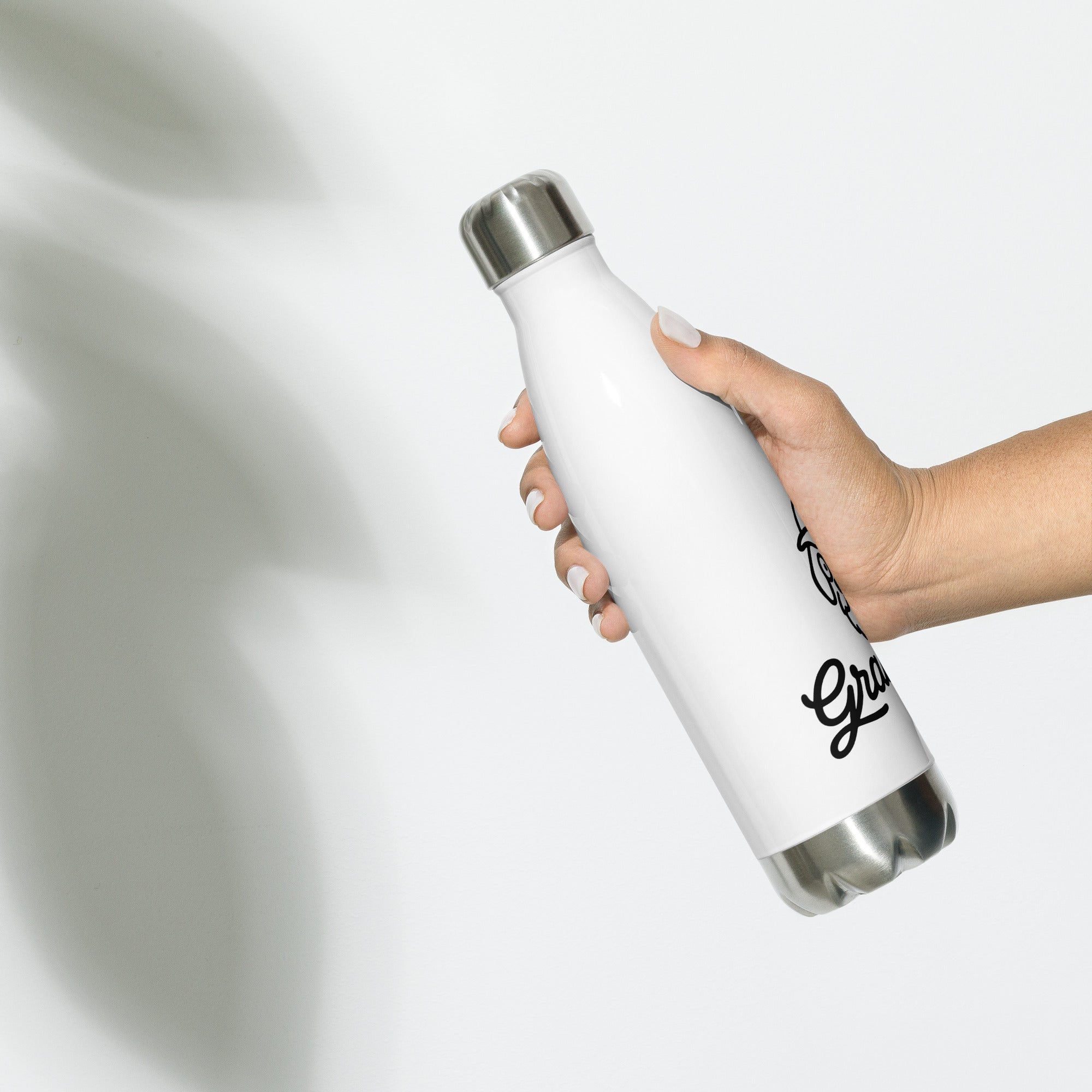 White water bottle with silver cap held by a hand on a light gray background