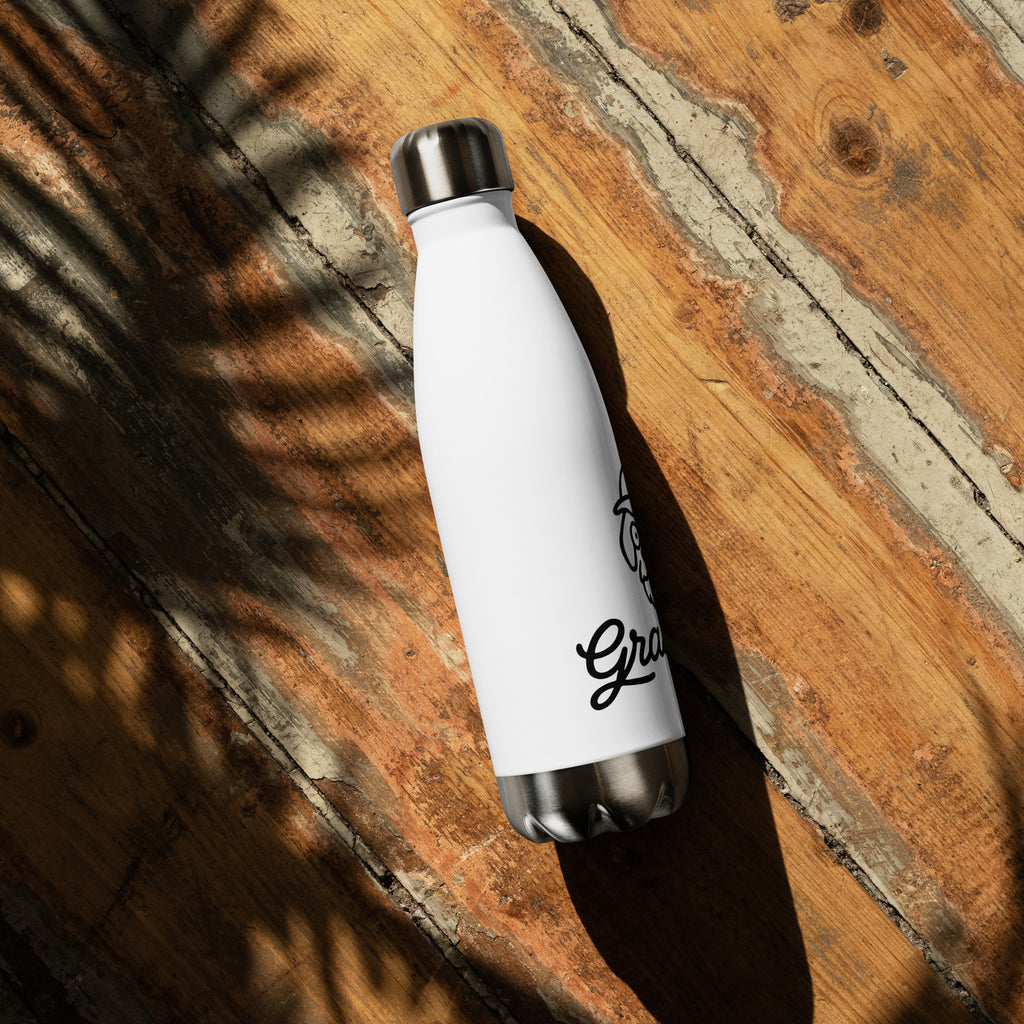White insulated bottle with silver cap on a wooden surface