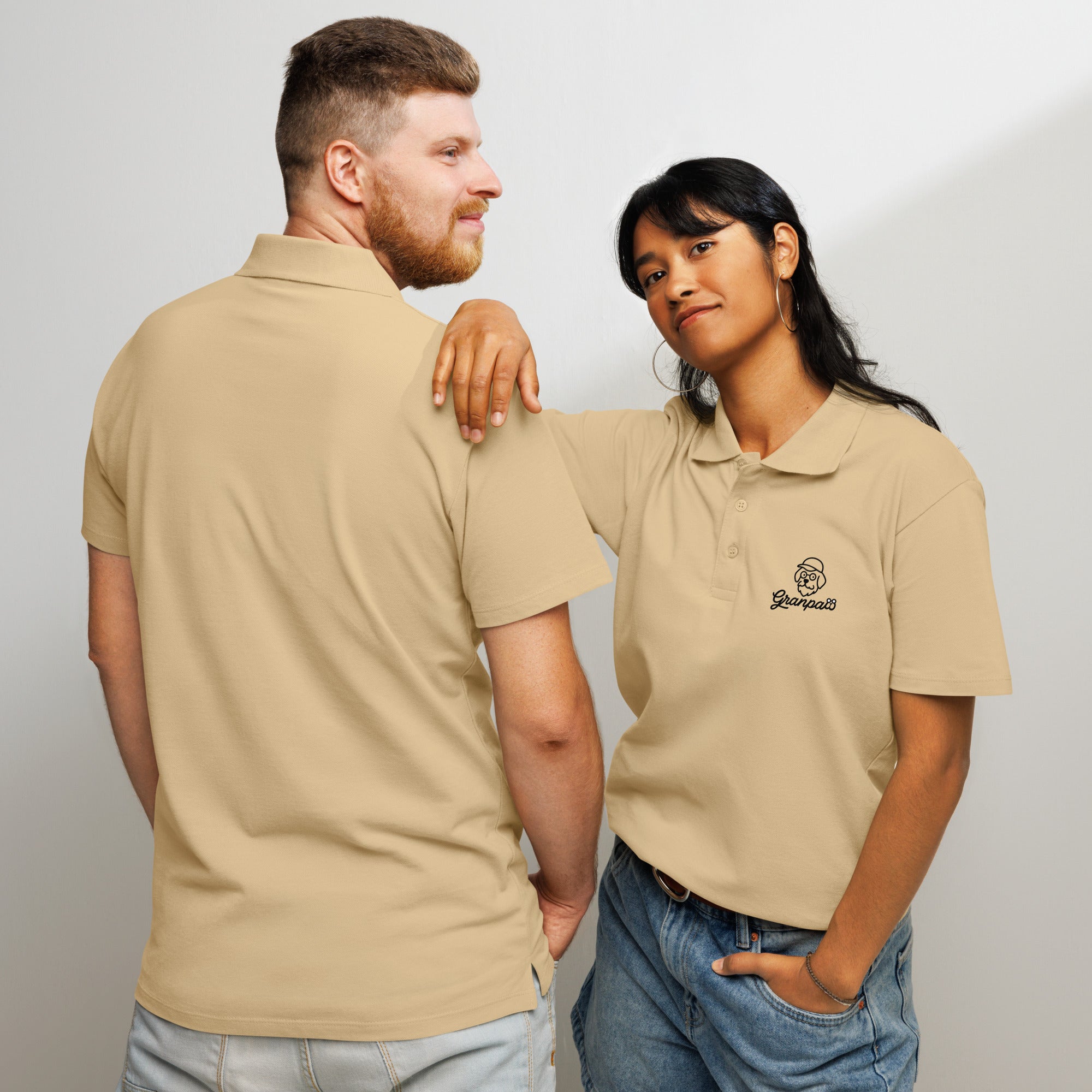 Two people wearing beige polo shirts with a logo on a plain background
