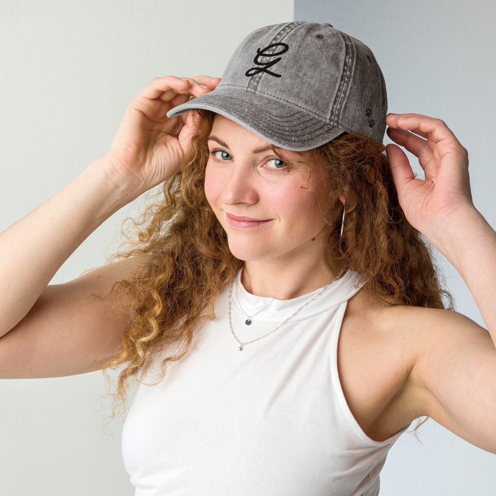 Woman wearing a gray cap with a logo, posing against a plain background
