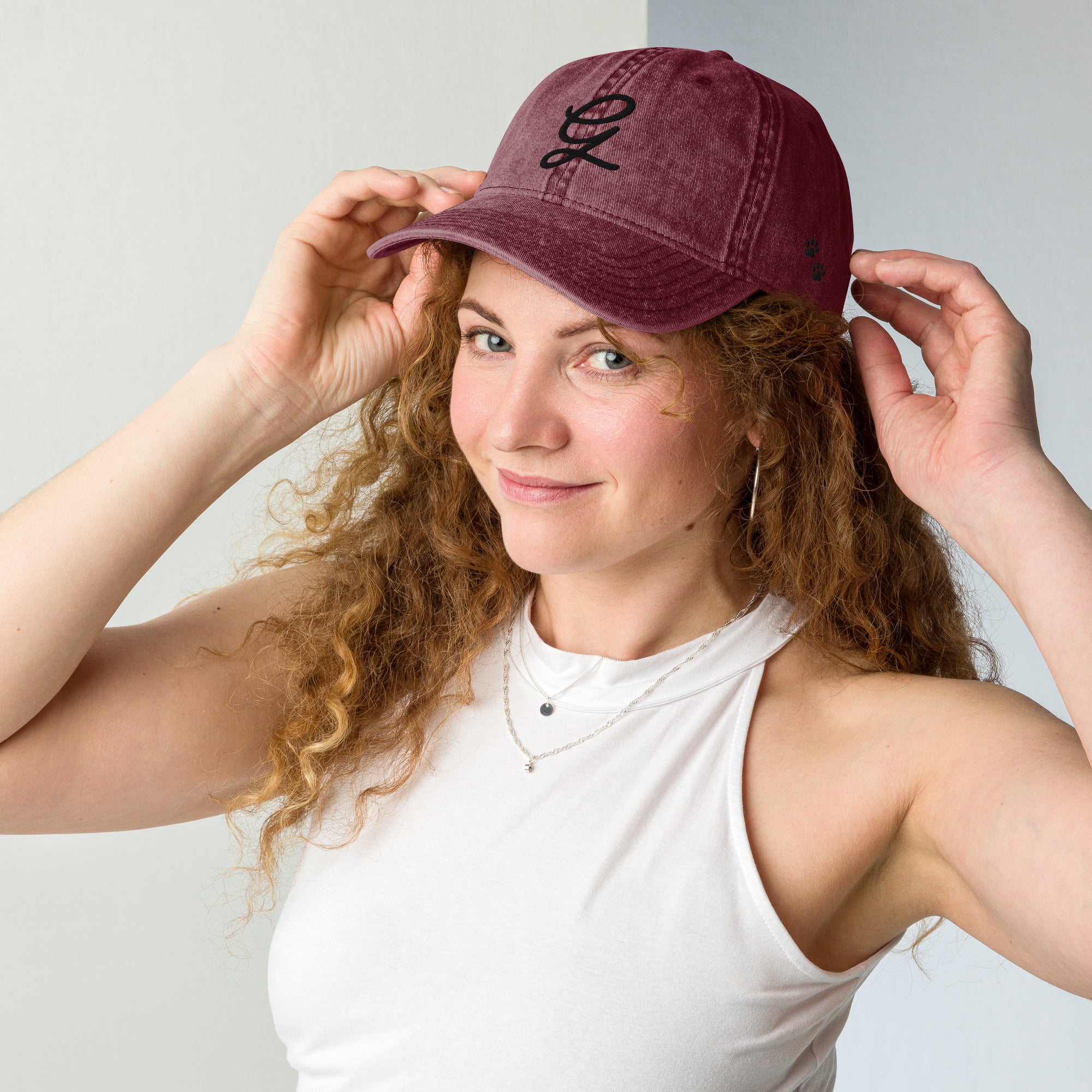 Woman wearing a maroon cap with a logo, posing against a plain background