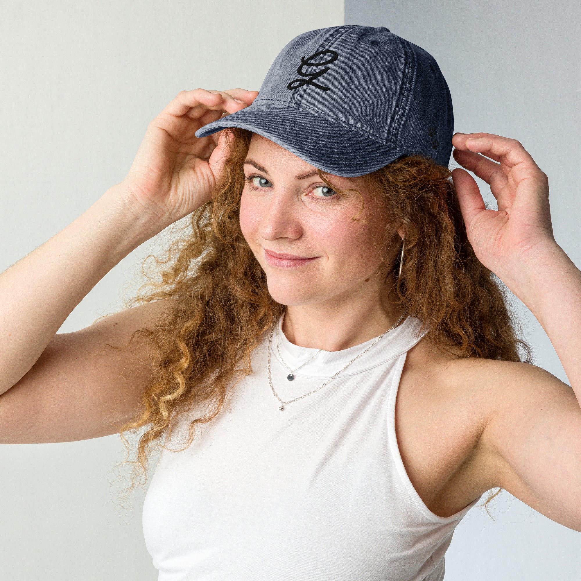 Woman wearing a denim cap with a logo, posing against a plain background