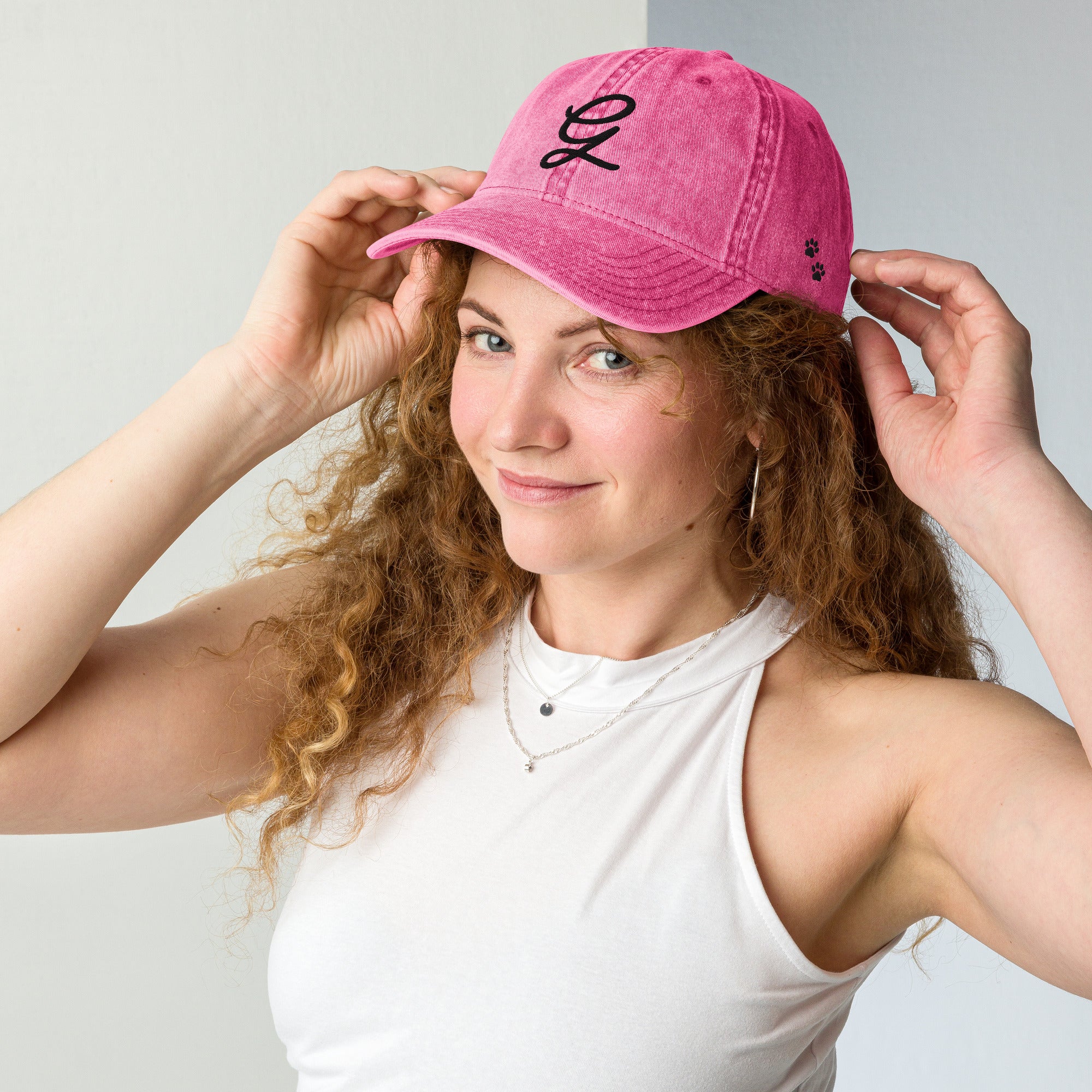 Woman wearing a pink cap with a logo, posing against a plain background