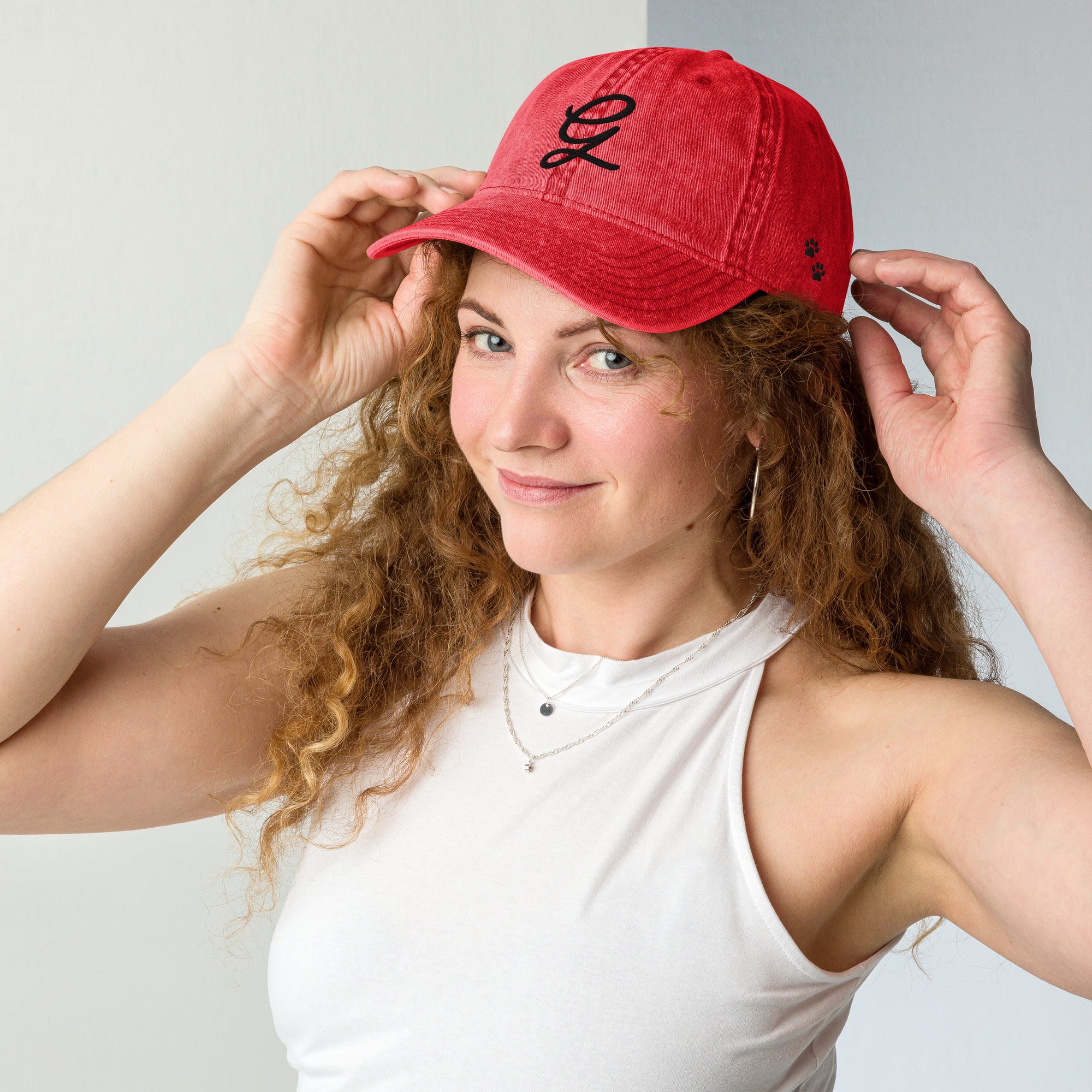 Woman wearing a red cap with a logo, posing against a plain background