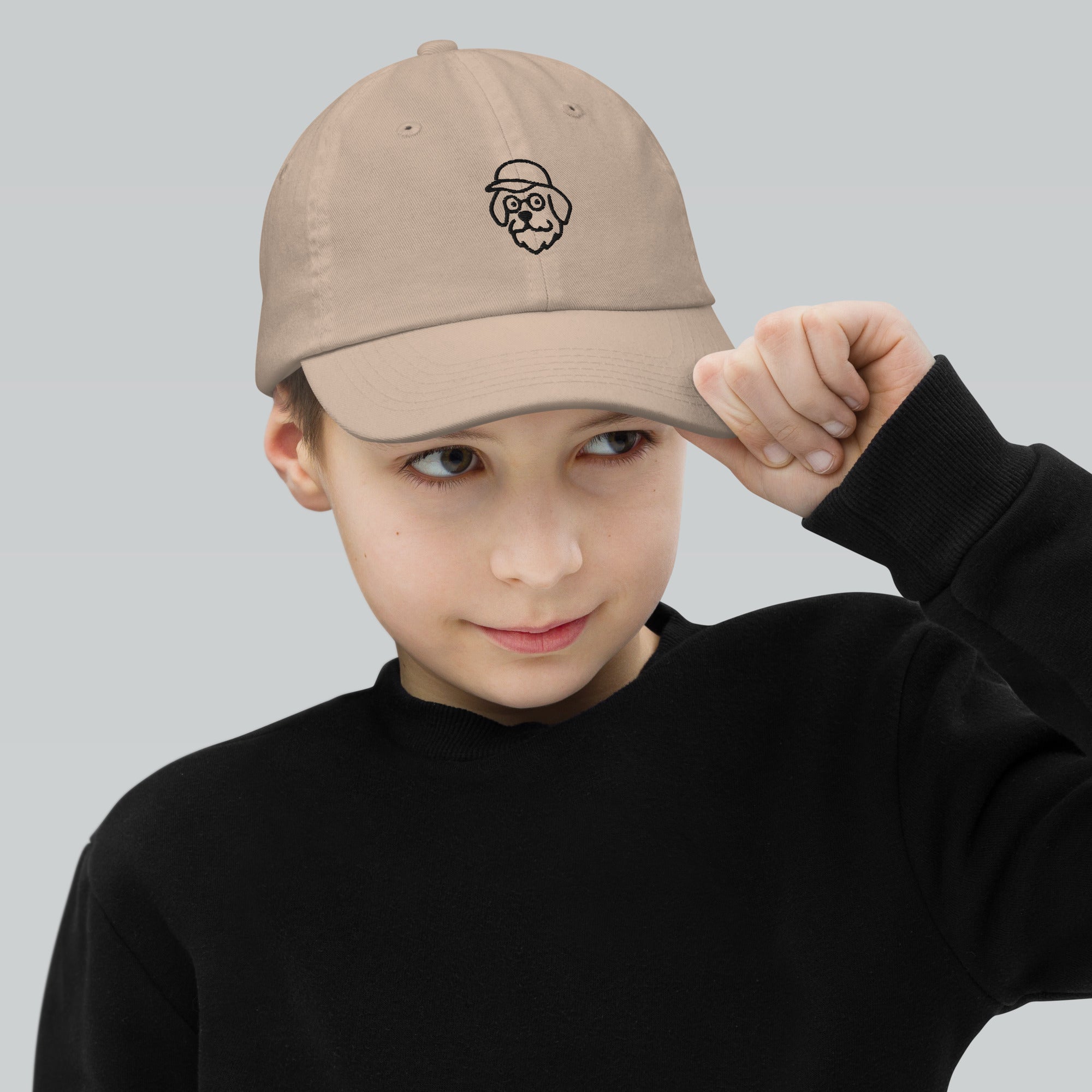 Child wearing a beige cap with a logo on a plain background