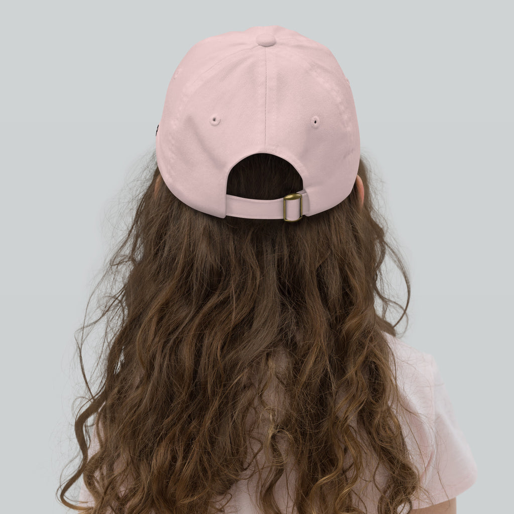 Person wearing a pink cap with long wavy hair on a light gray background