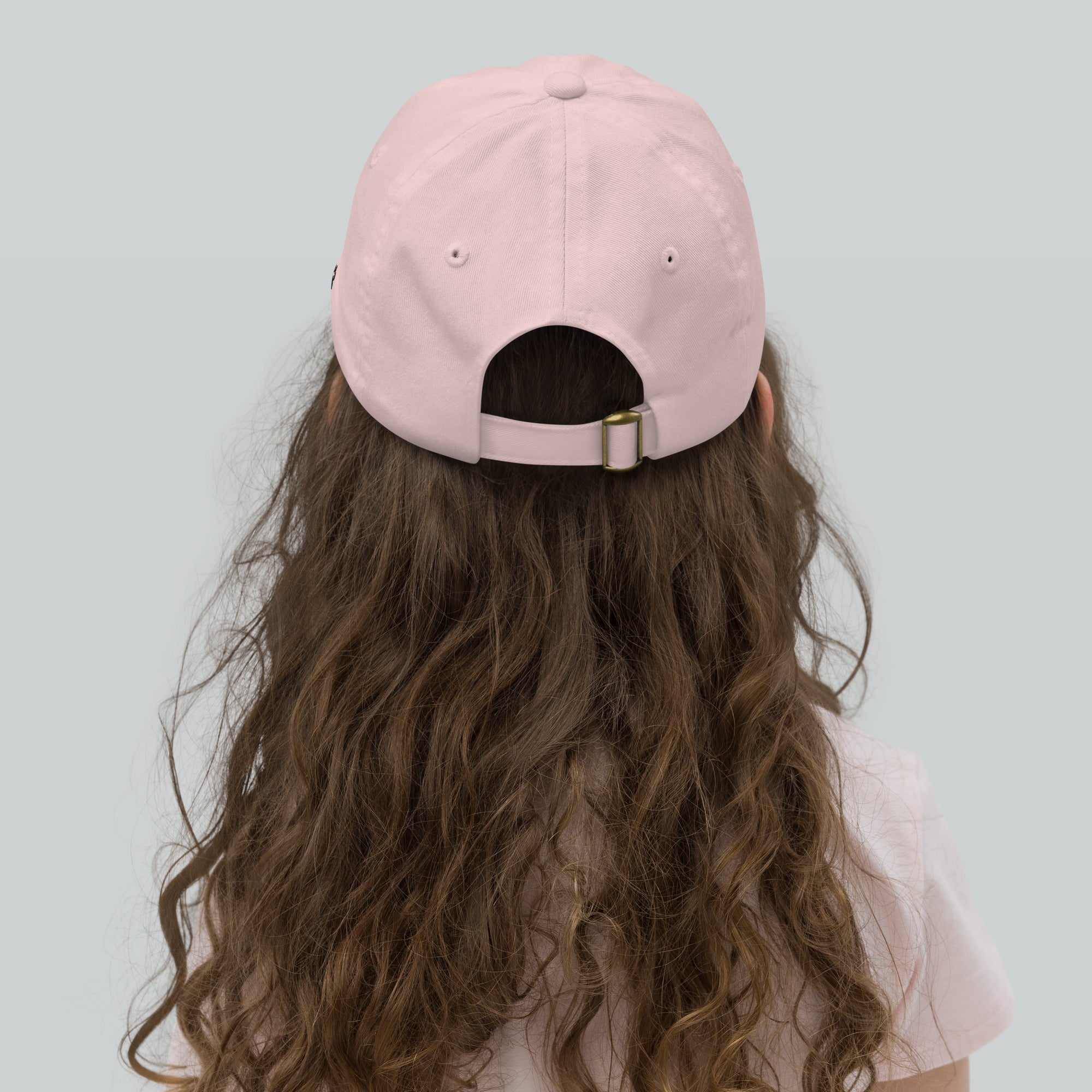 Person wearing a pink cap with long wavy hair on a light gray background