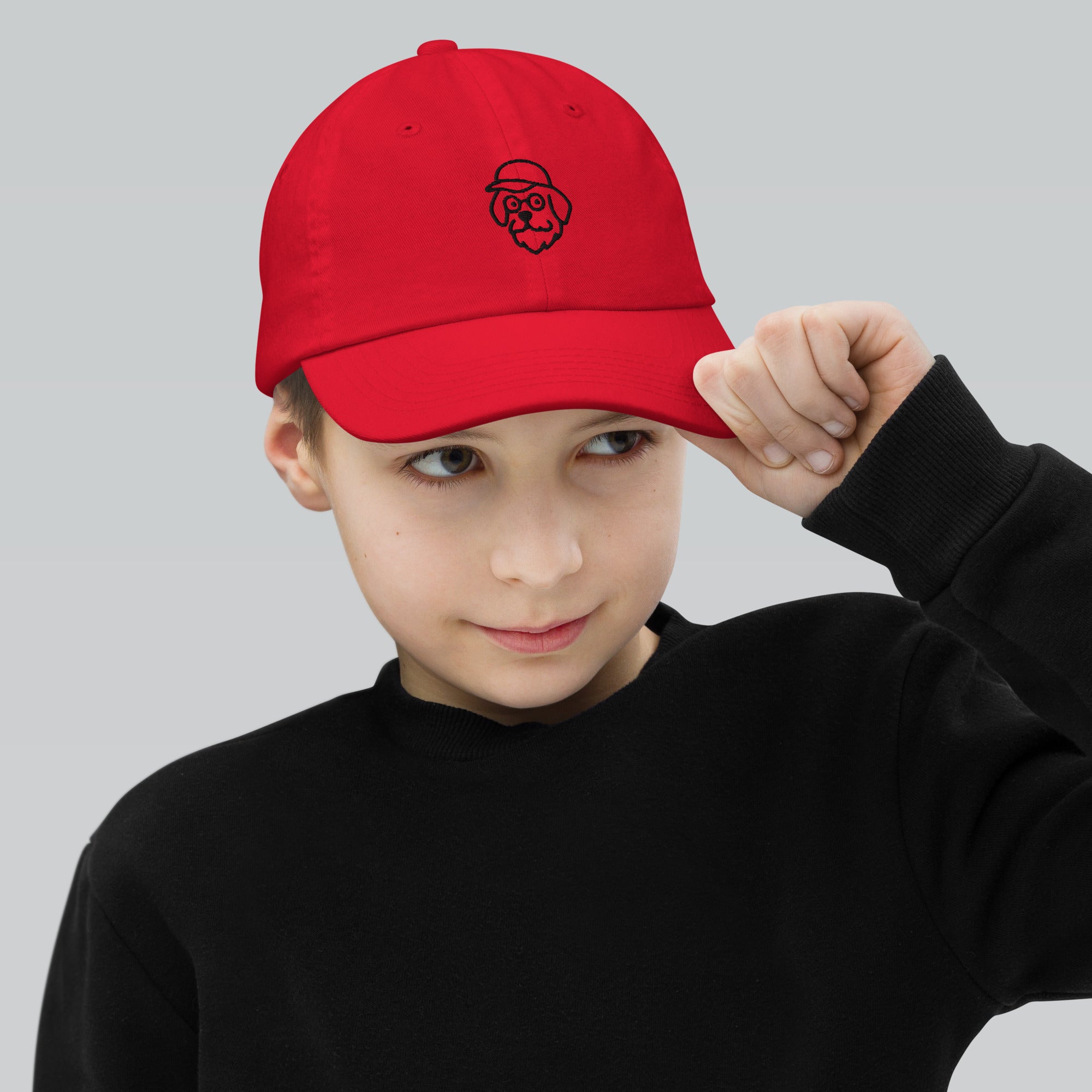 Child wearing a red cap with a logo on a gray background