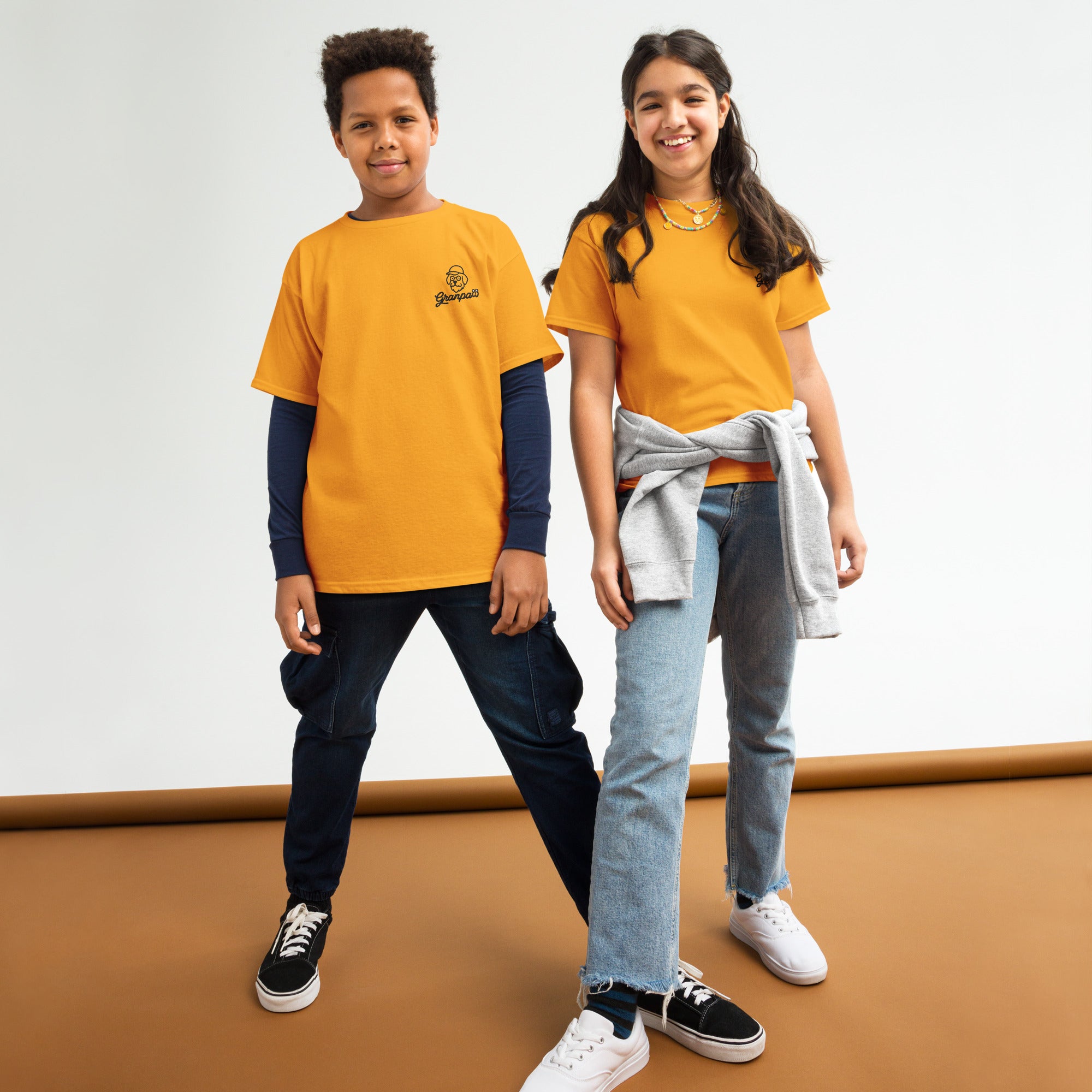 Two children wearing matching granpaw yellow t-shirts with a brand logo on a white background.