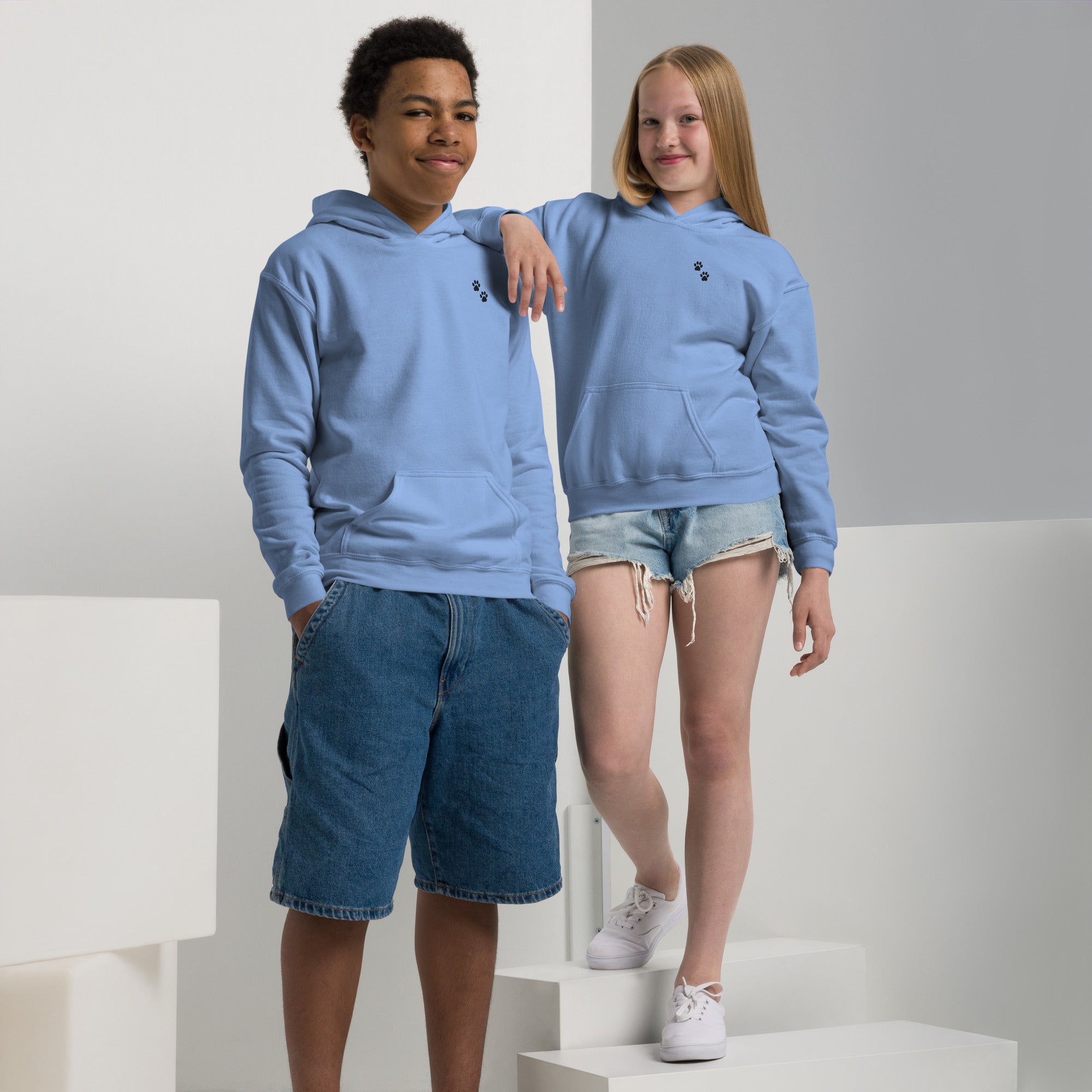 Two children wearing matching blue hoodies and shorts on a white background