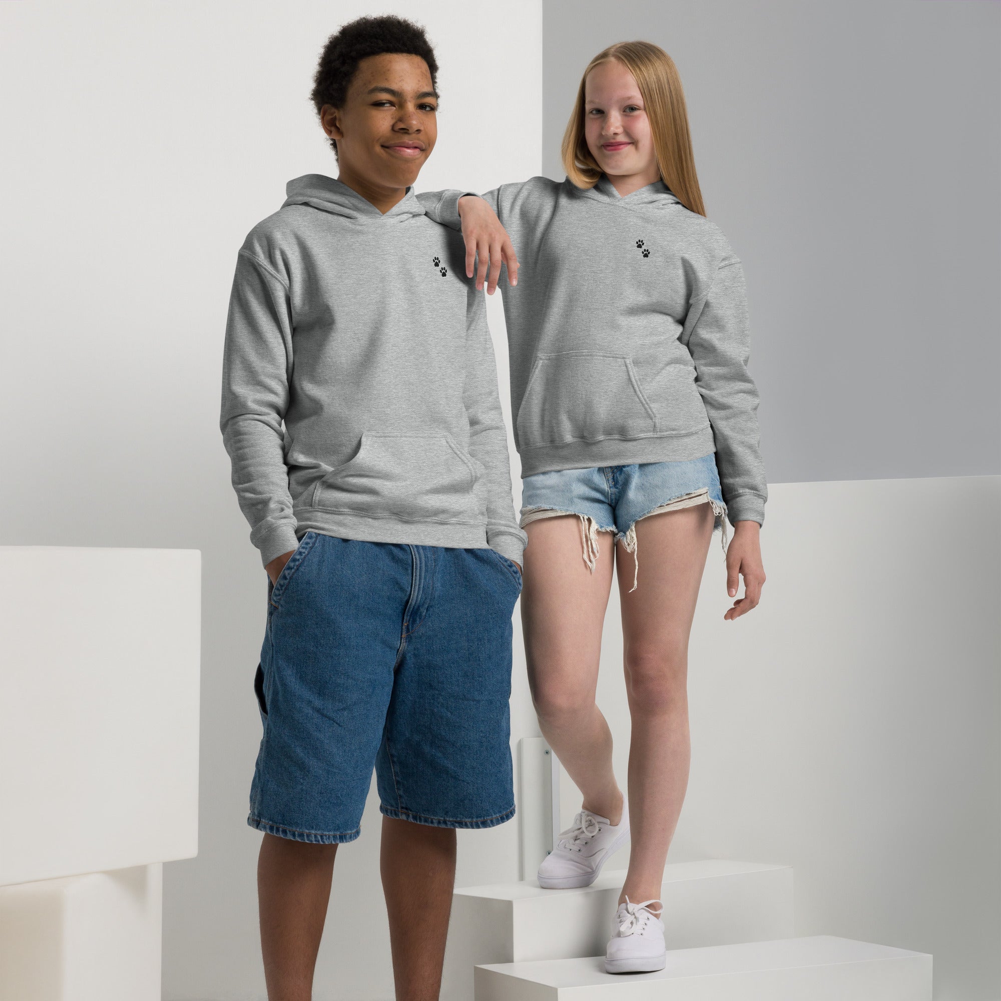 Two people wearing gray hoodies and denim shorts on a white background