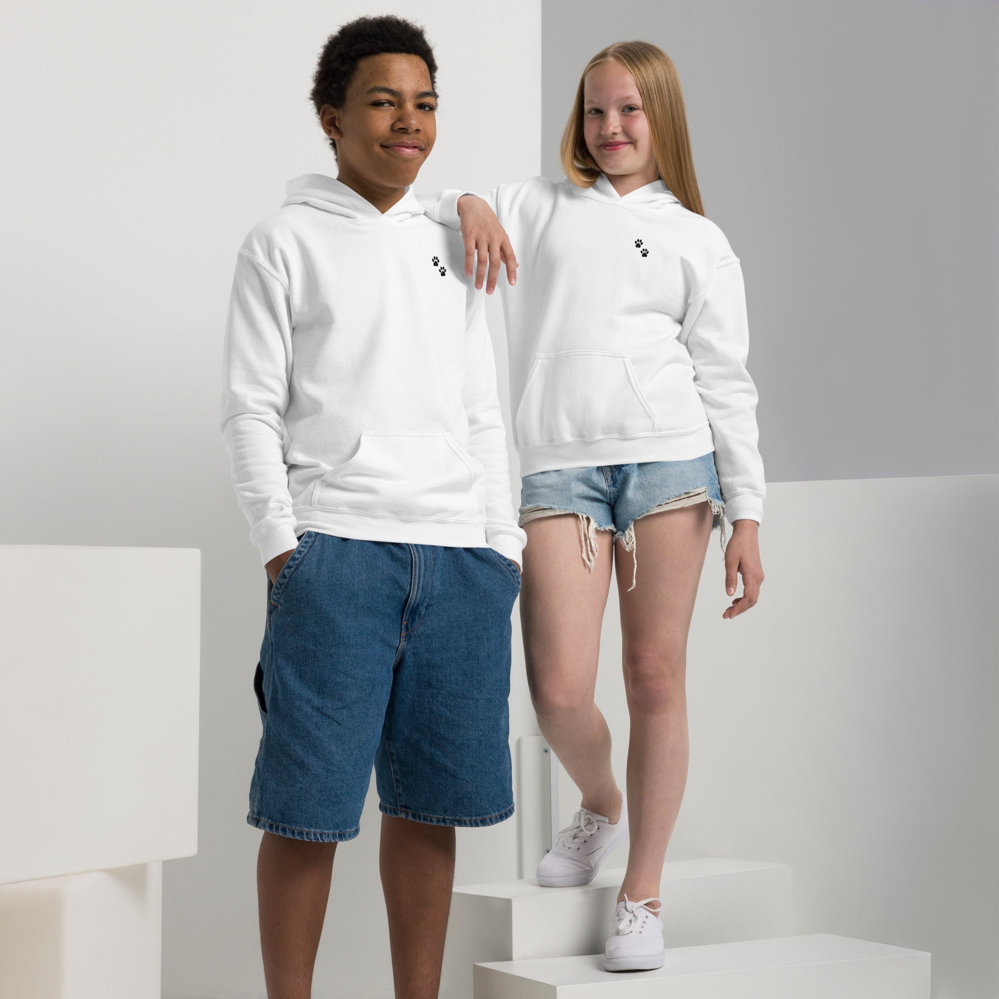 Two children wearing white hoodies and shorts on a white background